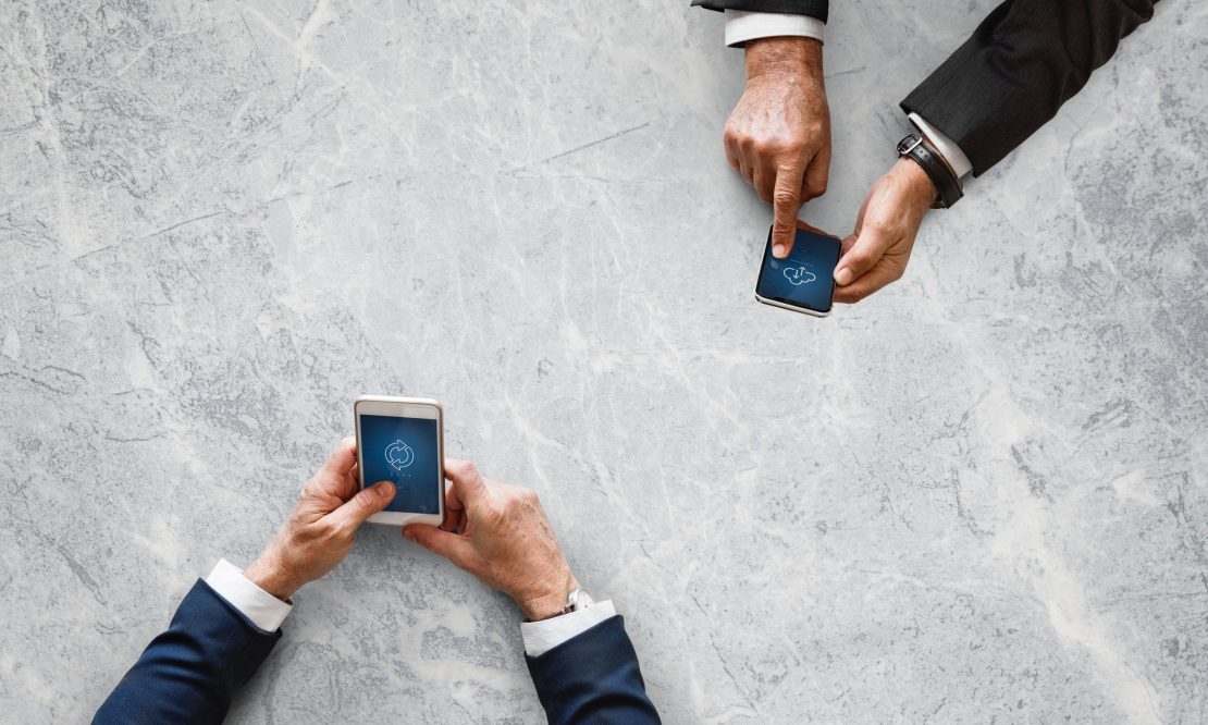 Two sets of hands working on mobile devices